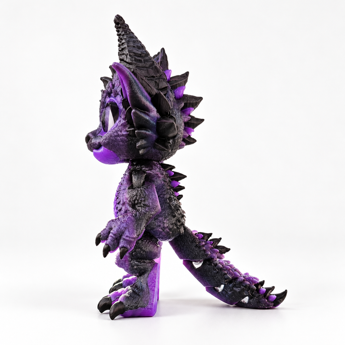 Side view of the purple and black Dragon Doll, showing its profile, back spikes, jointed body, tail, and support on a clean light background
